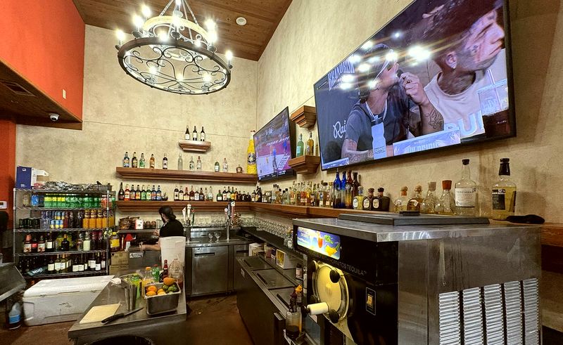 The bar, with shelves of bottles under a wrought iron chandelier.